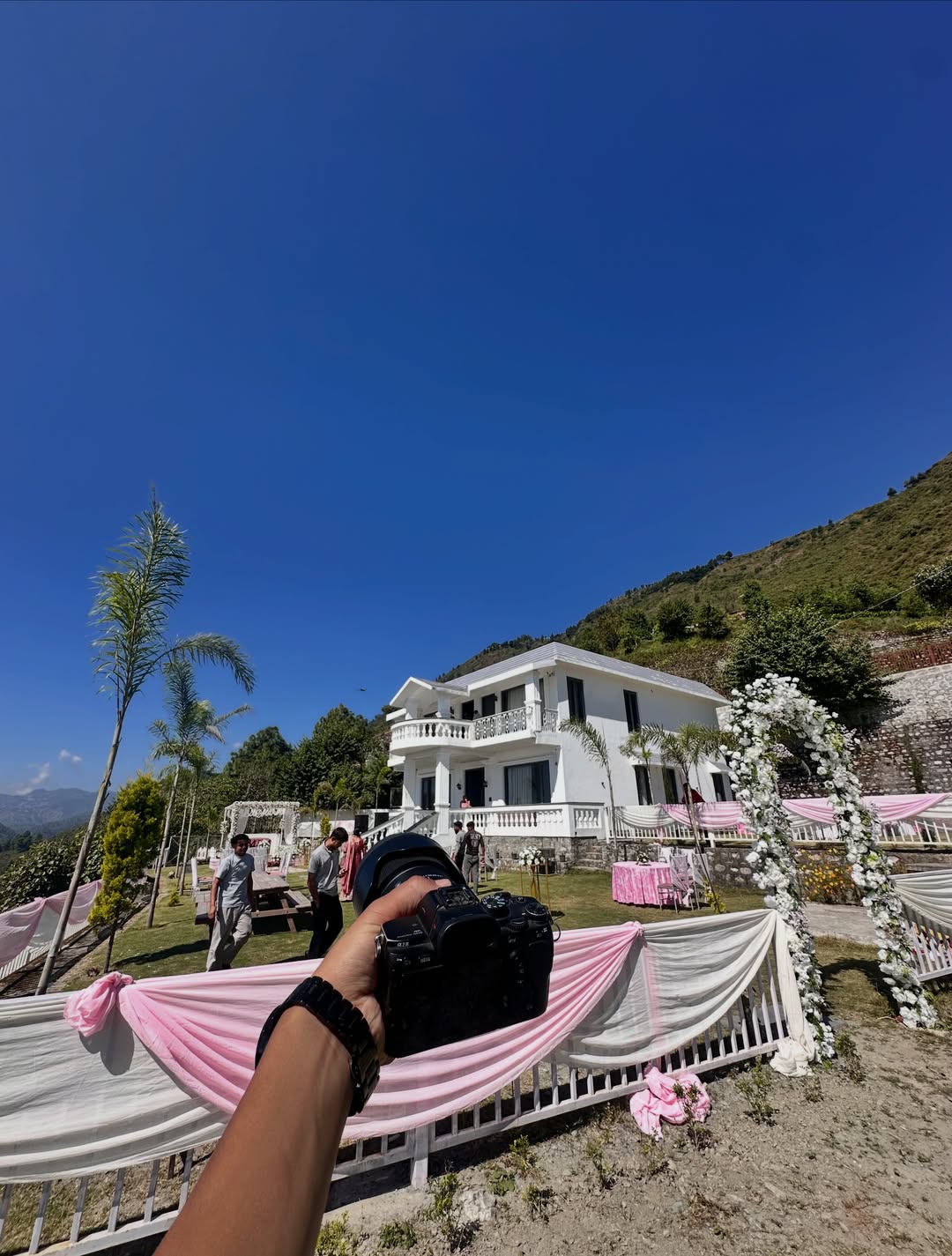 A photographer holding a Sony camera at a celebration venue in the hills of Bhimtal