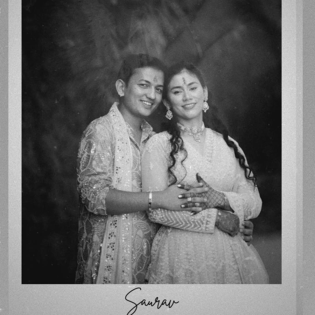 A black and white engagement portrait of a smiling couple in traditional outfits